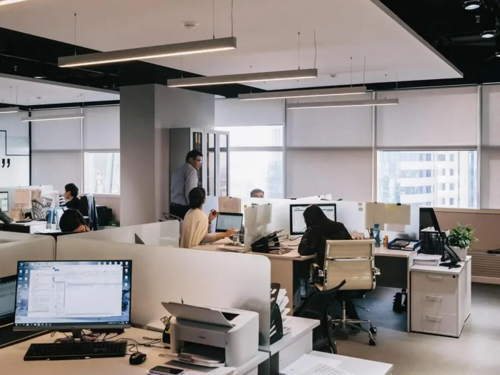 employees sat at office desks in office chairs in open plan office