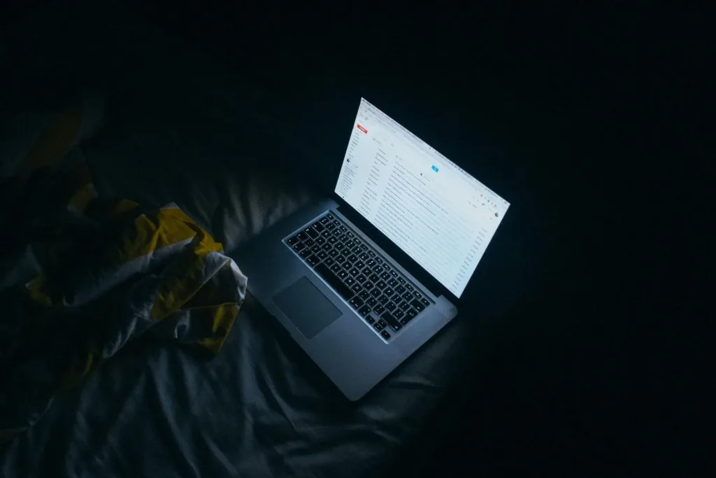 laptop screen glowing with blue light in dark room