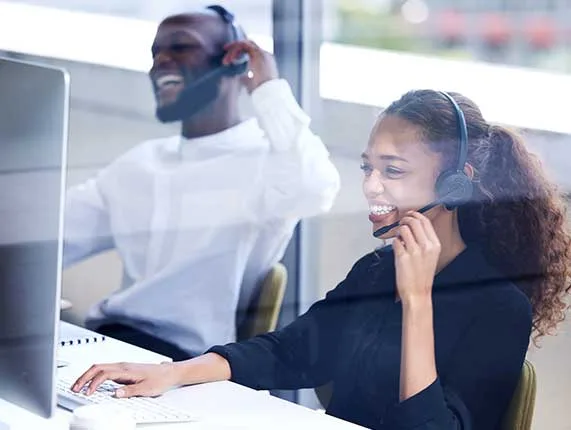 Two people smiling while on the phone. 
